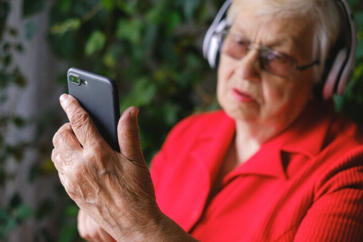 a man in red shirt using a phone while wearing headphones