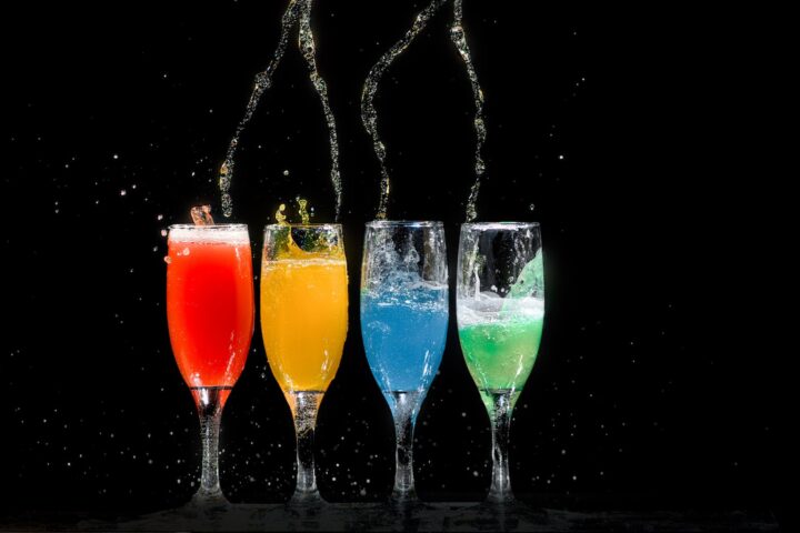 four champagne flutes with assorted color liquids